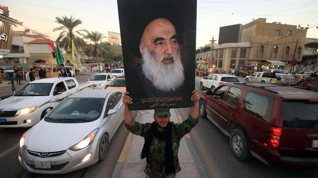 أحد اعضاء الحشد الشعبي يرفع صورة السيستاني