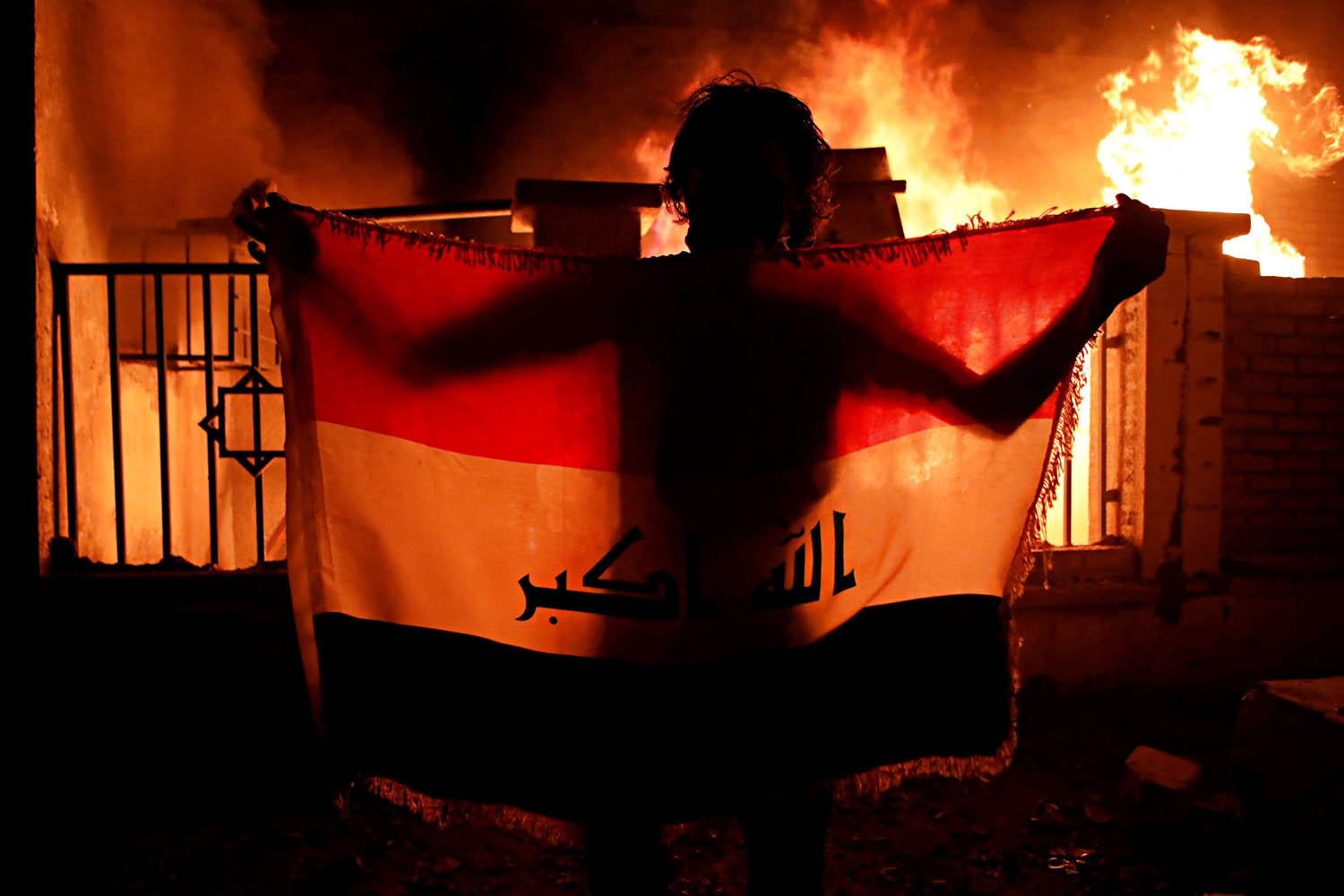 عراقي يرفع علما أمام مبنى البلدية المحترق في البصرة
