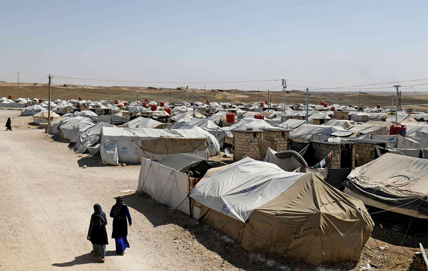 Women walk at a camp for Islamic State (IS) group-affiliated people in the northern Syrian village of Malikiya 