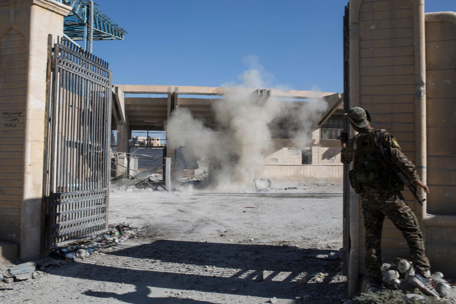 A member of the U.S.-backed Syrian Democratic Forces SDF throws a bomb to check for more explosives as they clear the stadium that was the site of Islamic State fighters' last stand in the city of Raqqa, Syria.