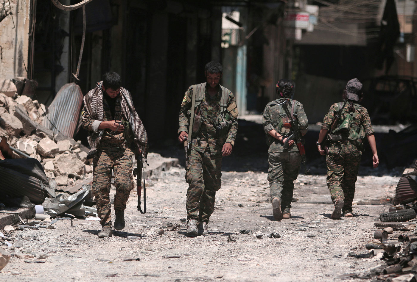Syria Democratic Forces (SDF) fighters walk on the rubble of damaged shops and buildings in the city of Manbij, in Aleppo Governorate, Syria, August 10, 2016. 