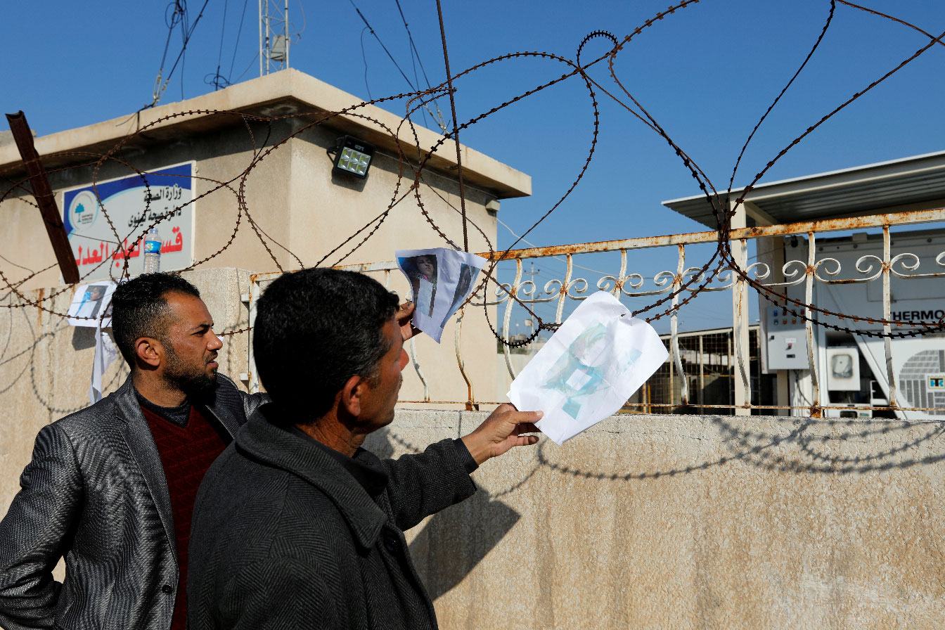 People look at pictures of victims, after a ferry sank in the Tigris river, outside a morgue in Mosul, Iraq March 22, 2019.