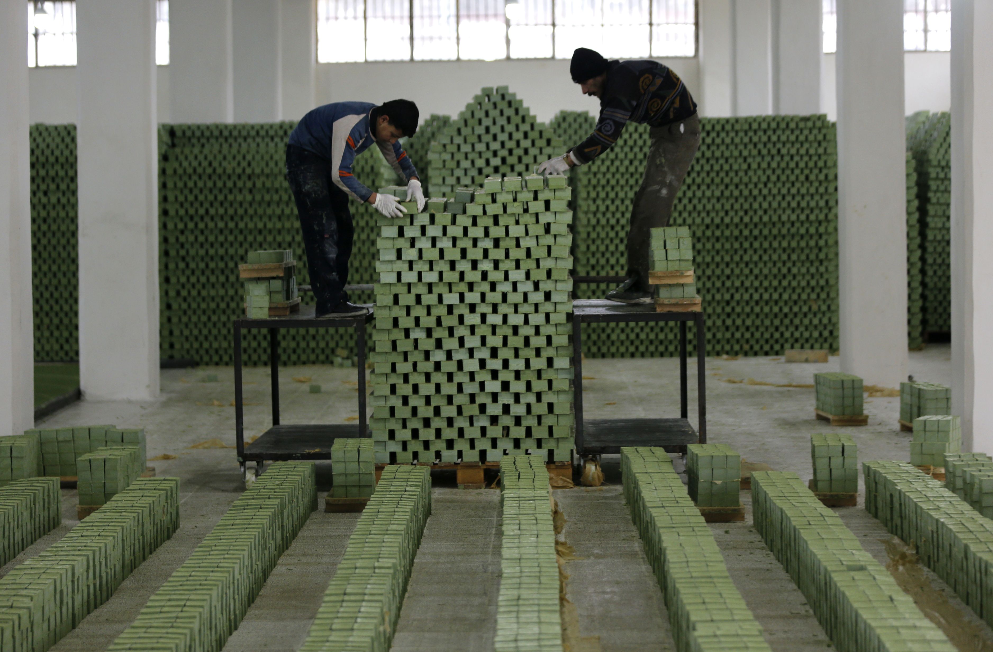 Syrian workers arrange olive soap bars in a factory on the outskirts of Aleppo on February 10, 2019.