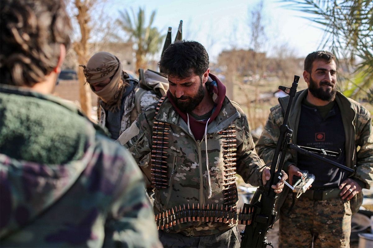 Syrian Democratic Forces (SDF) stand at a makeshift camp for IS group members and their families in Baghouz