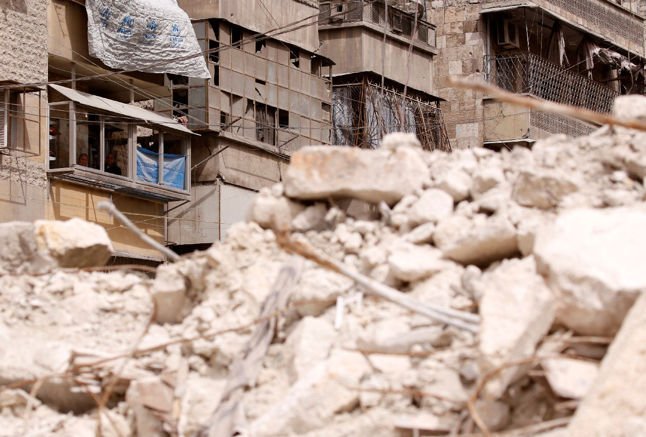 Malak Kasas' grandfather and uncle look out from their balcony overlooking rubble where she is still buried
