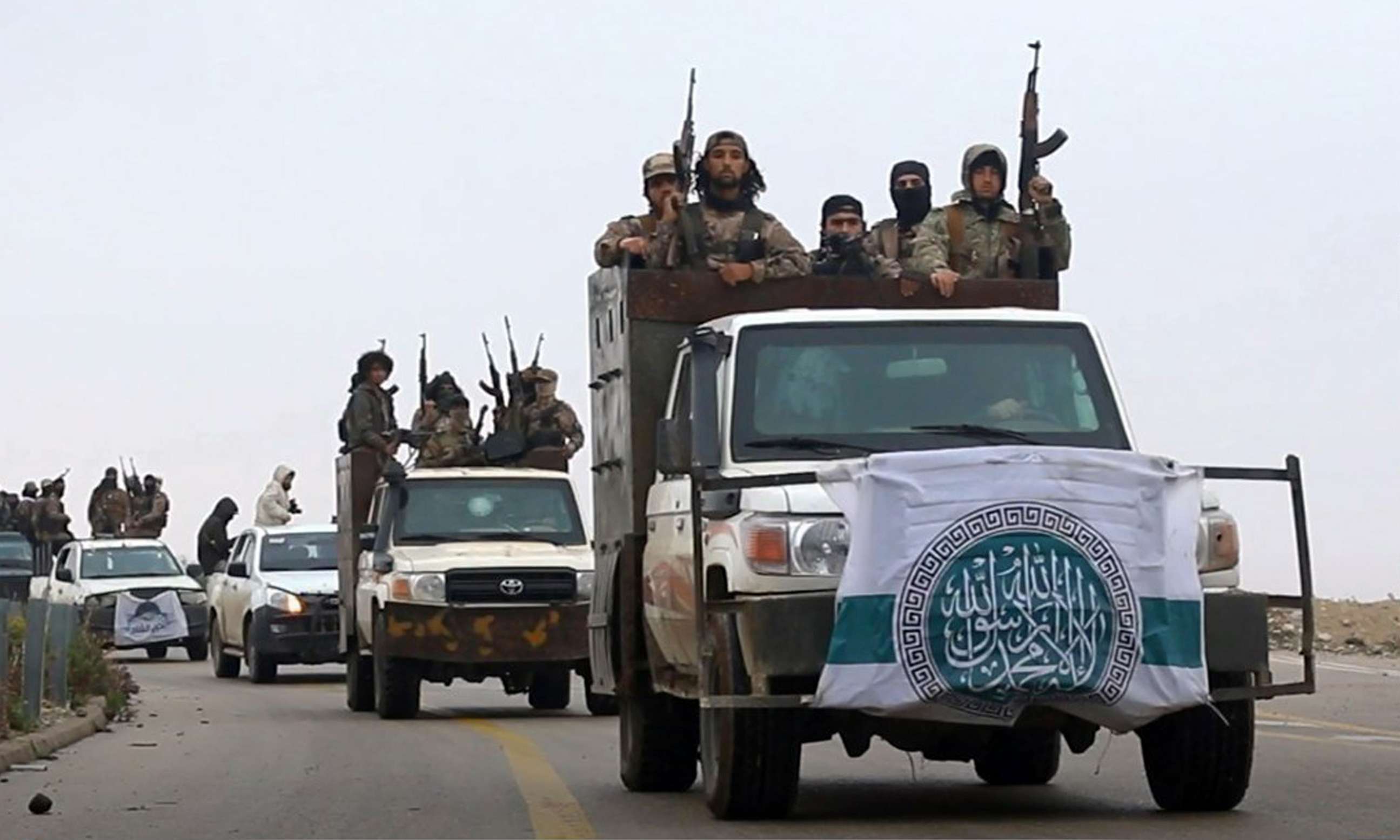 HTS fighters driving their vehicles during a military drill in northern Syria