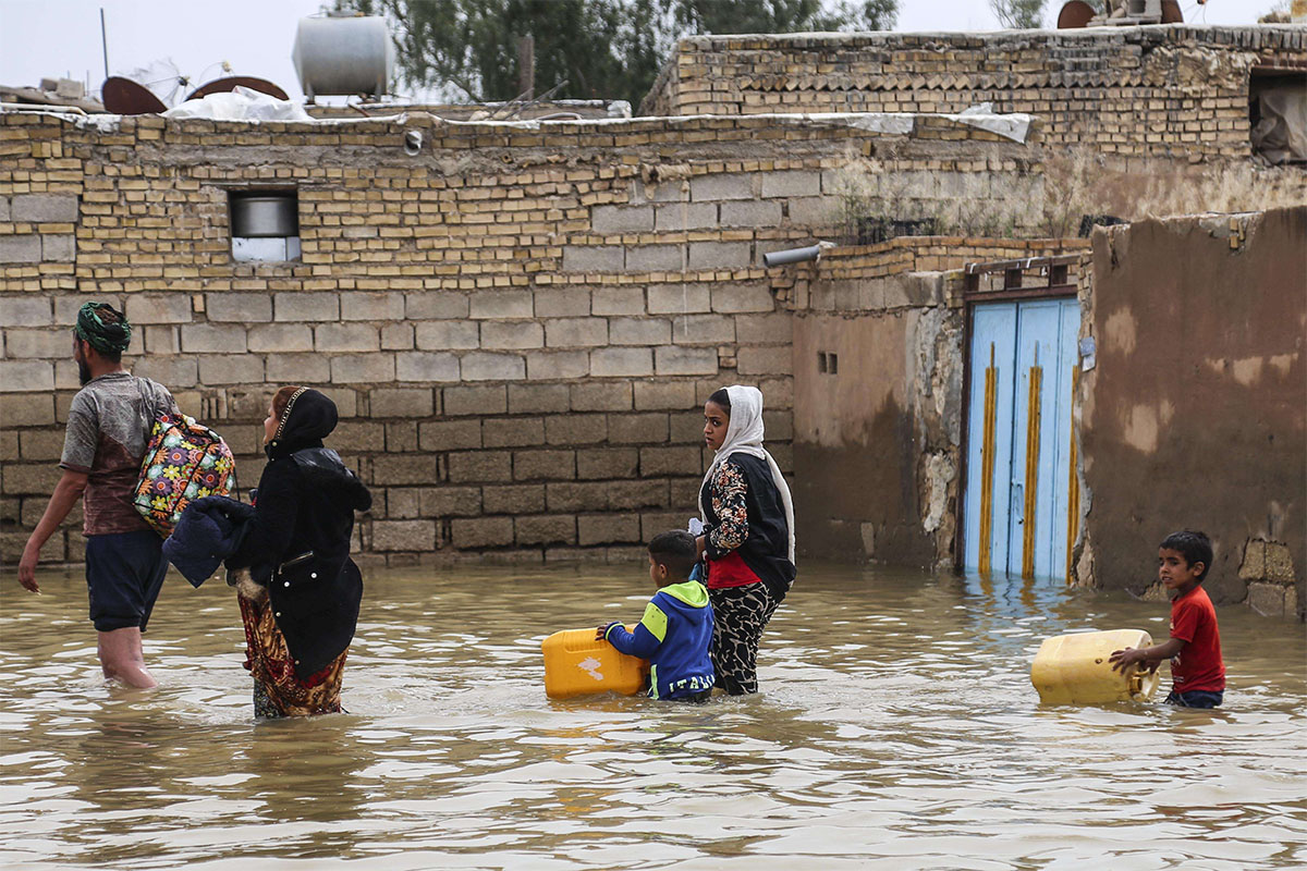 An Iranian family walks through a flooded street in a village around the city of Ahvaz