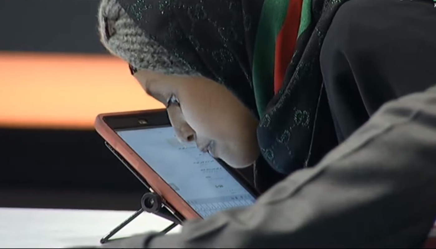 لقطة شاشة من التلفزيون الرسمي السعودي للجين الثقفي اثناء تعاملها مع كمبيوتر لوحي عبر أنفها