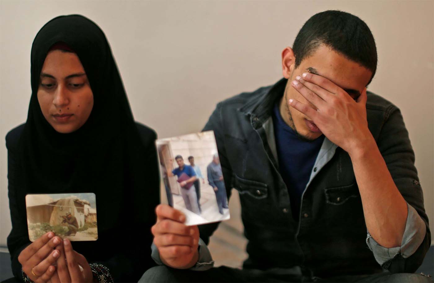 The daughter (L) and son of Zaki Mubarak hold his picture