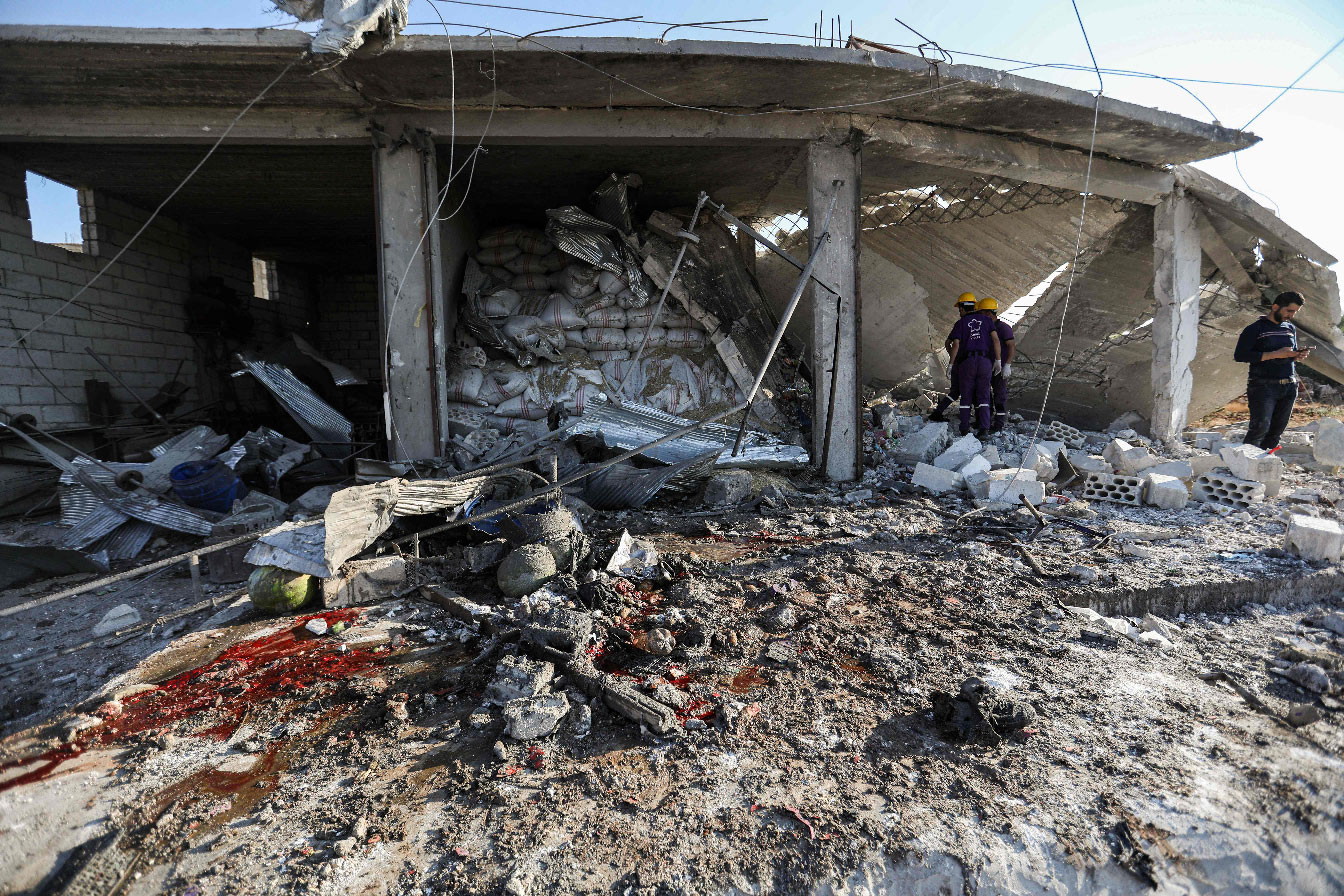 Members of the Syrian Civil Defence attempt to clear debris as they search for bodies