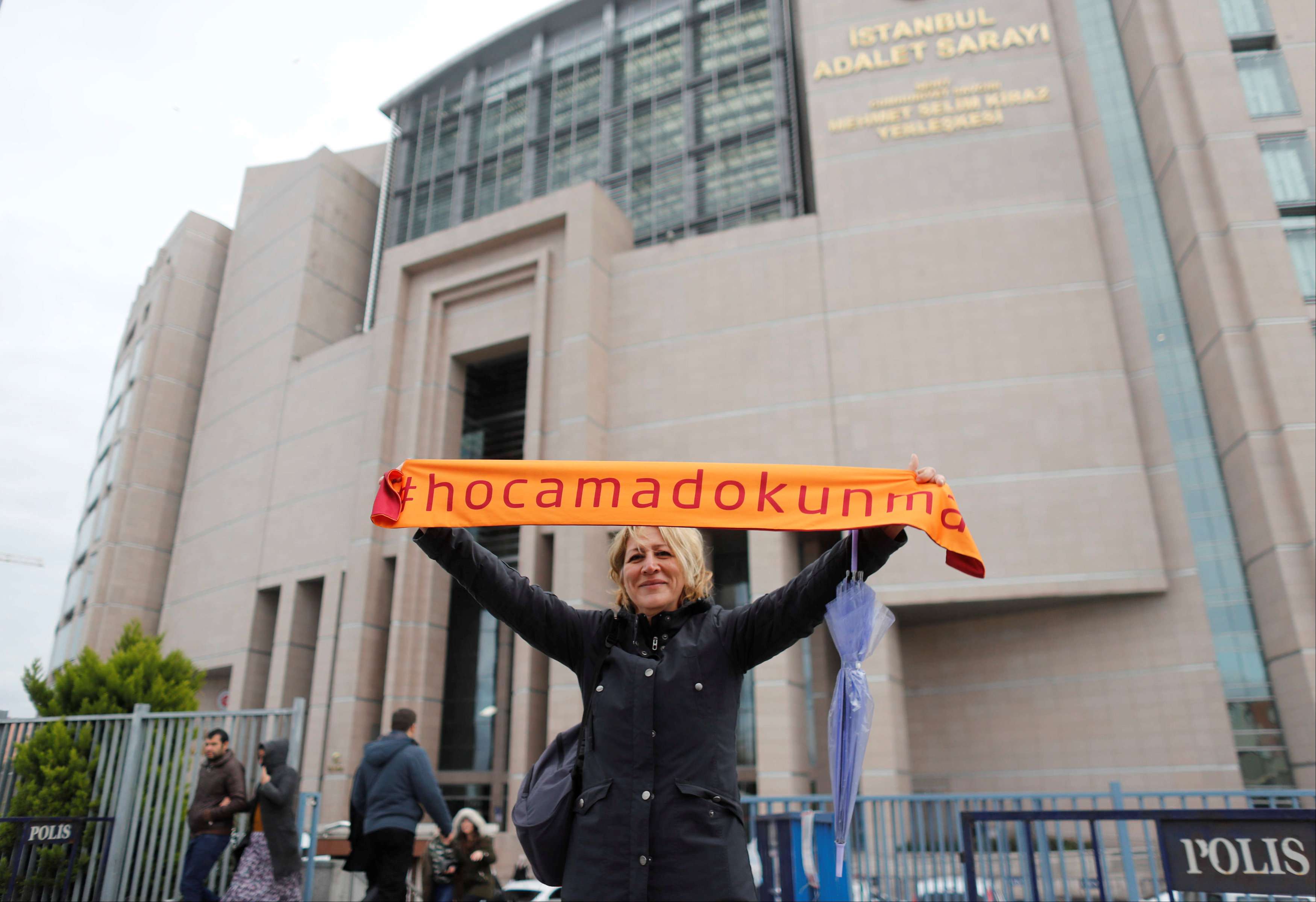 A demonstrator holds scarf reading "Do not touch my Academics"