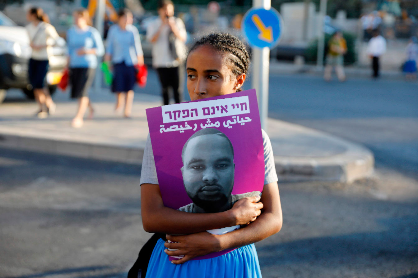 A woman holds a poster of Solomon Teka, who was shot dead by an off-duty police officer
