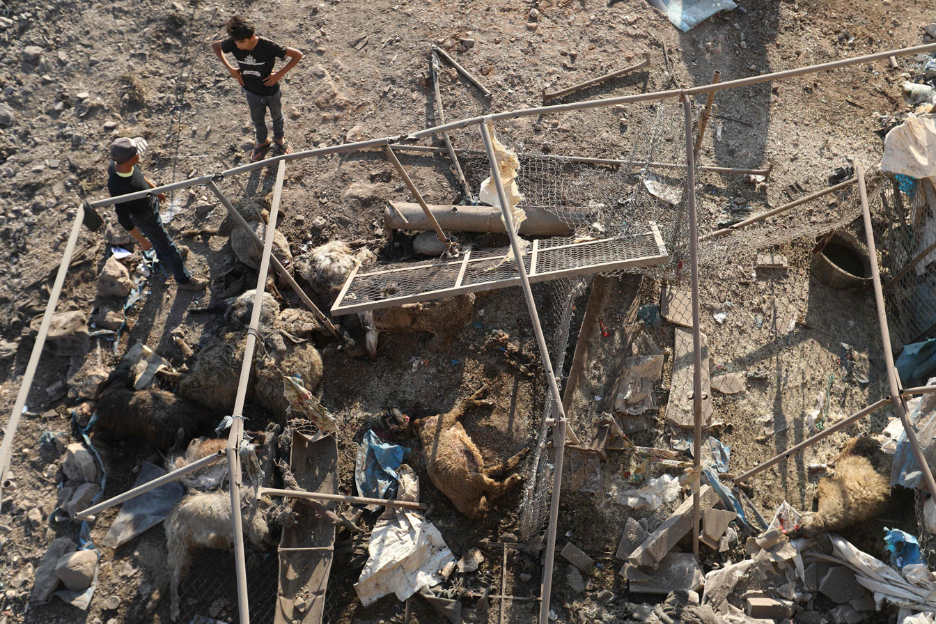 Syrian boys look at a destroyed sheep pen following a reported Russian air strike in Idlib province