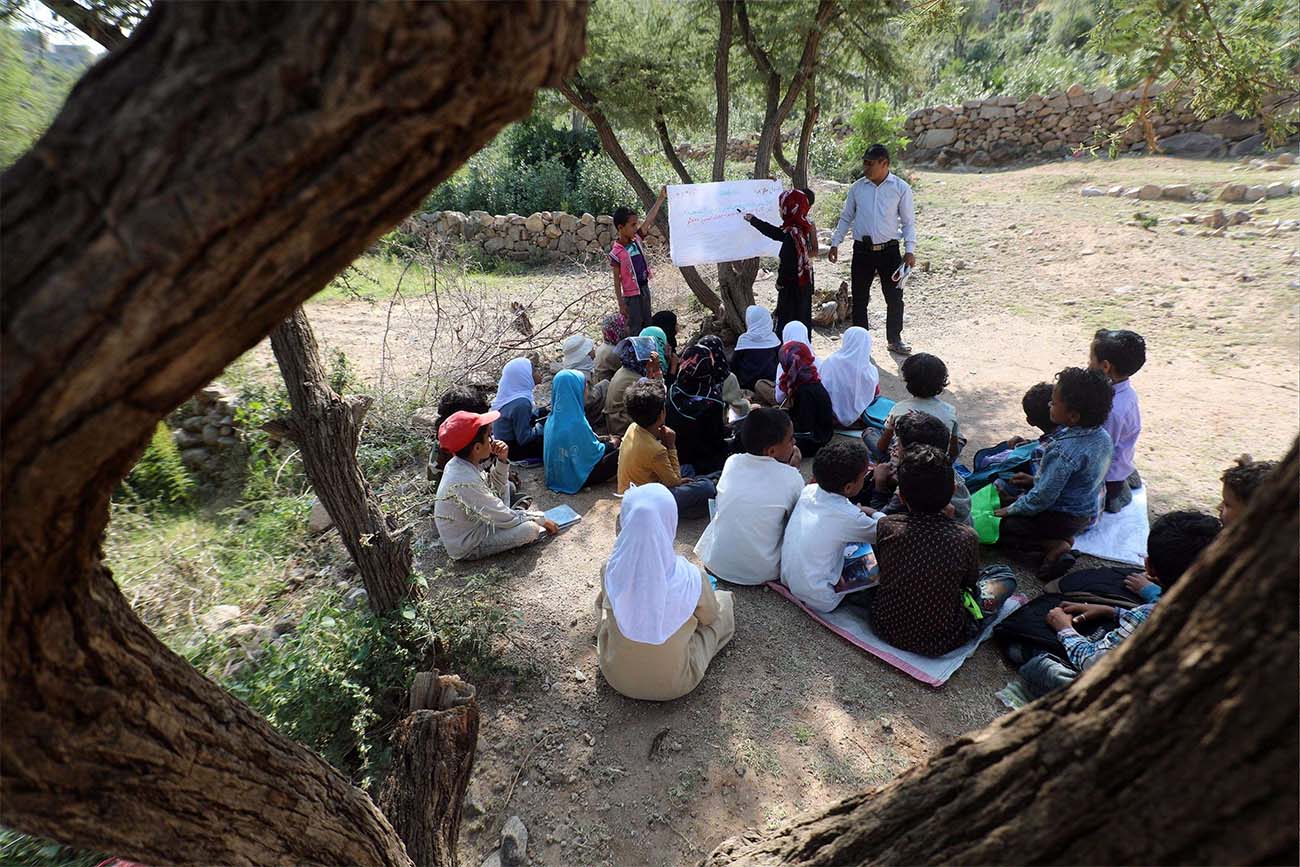 School children attend an open-air class under a tree near their unfinished school in the southwestern Yemeni village of al-Kashar