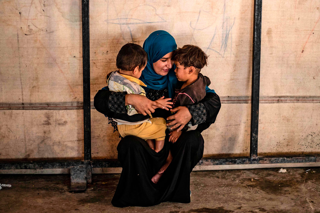 Volunteer caring for children linked with foreign fighters of the Islamic State, holds two at a camp in the village of Ain Issa