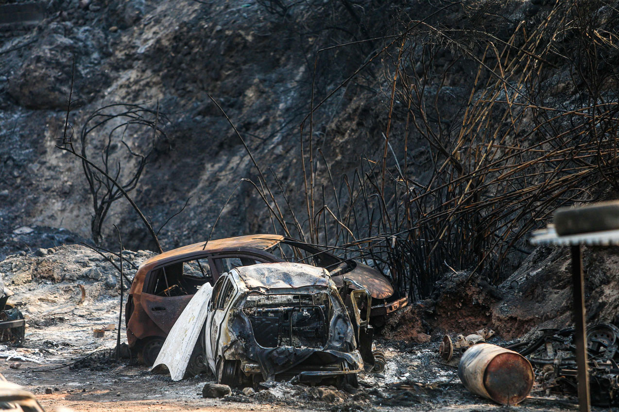 Vehicles lying on the side of a road, after they were burnt by fires near the town of Damour in Lebanon's Chouf mountains