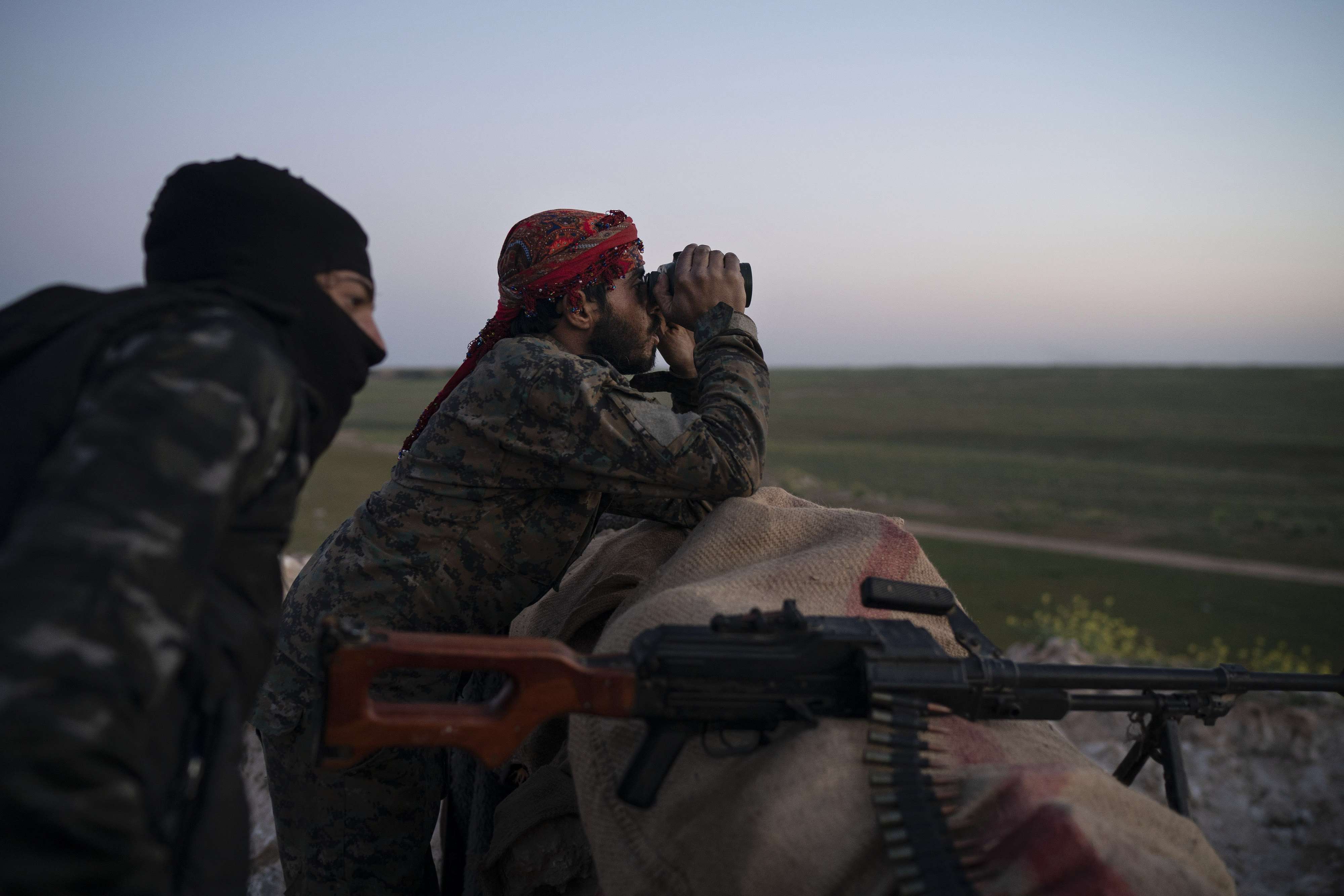 US backed Syrian Democratic Forces fighters survey a position in Baghouz, Syria