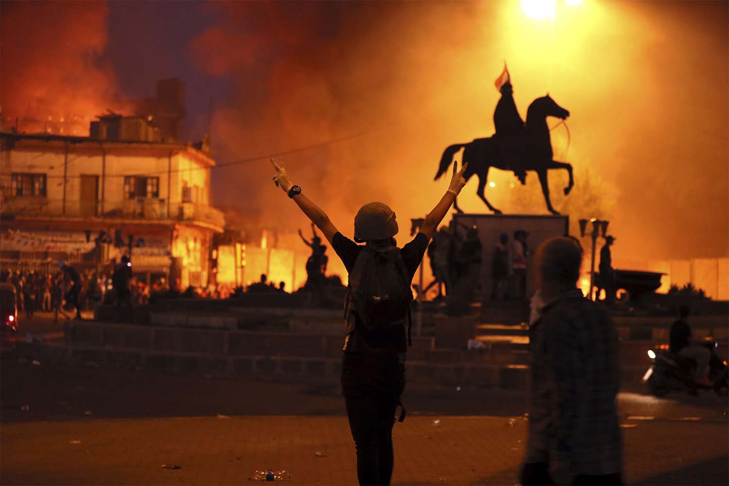Anti-government protests set fire while security forces fired live ammunition and tear gas near the state-run TV in Baghdad
