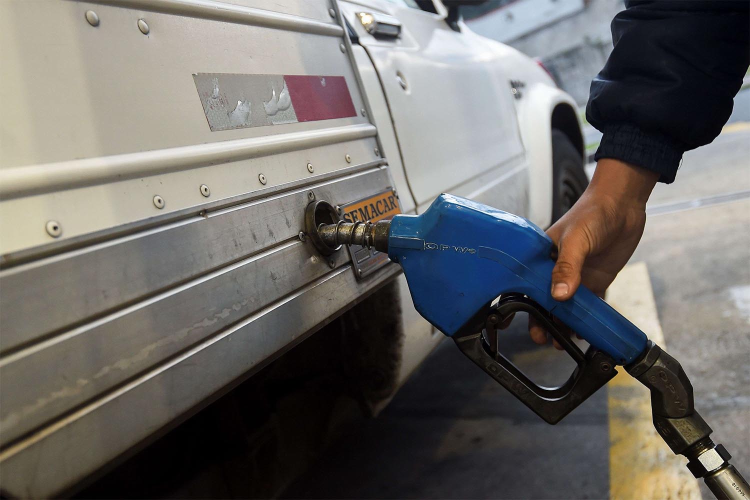 A worker refuels a truck at a gas station