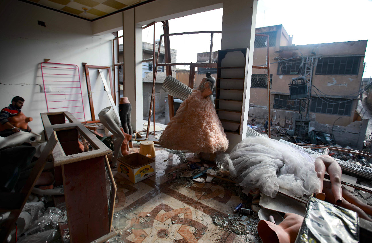 Wedding dresses are seen in the destroyed window of a bridal shop in a damaged building in Balyun