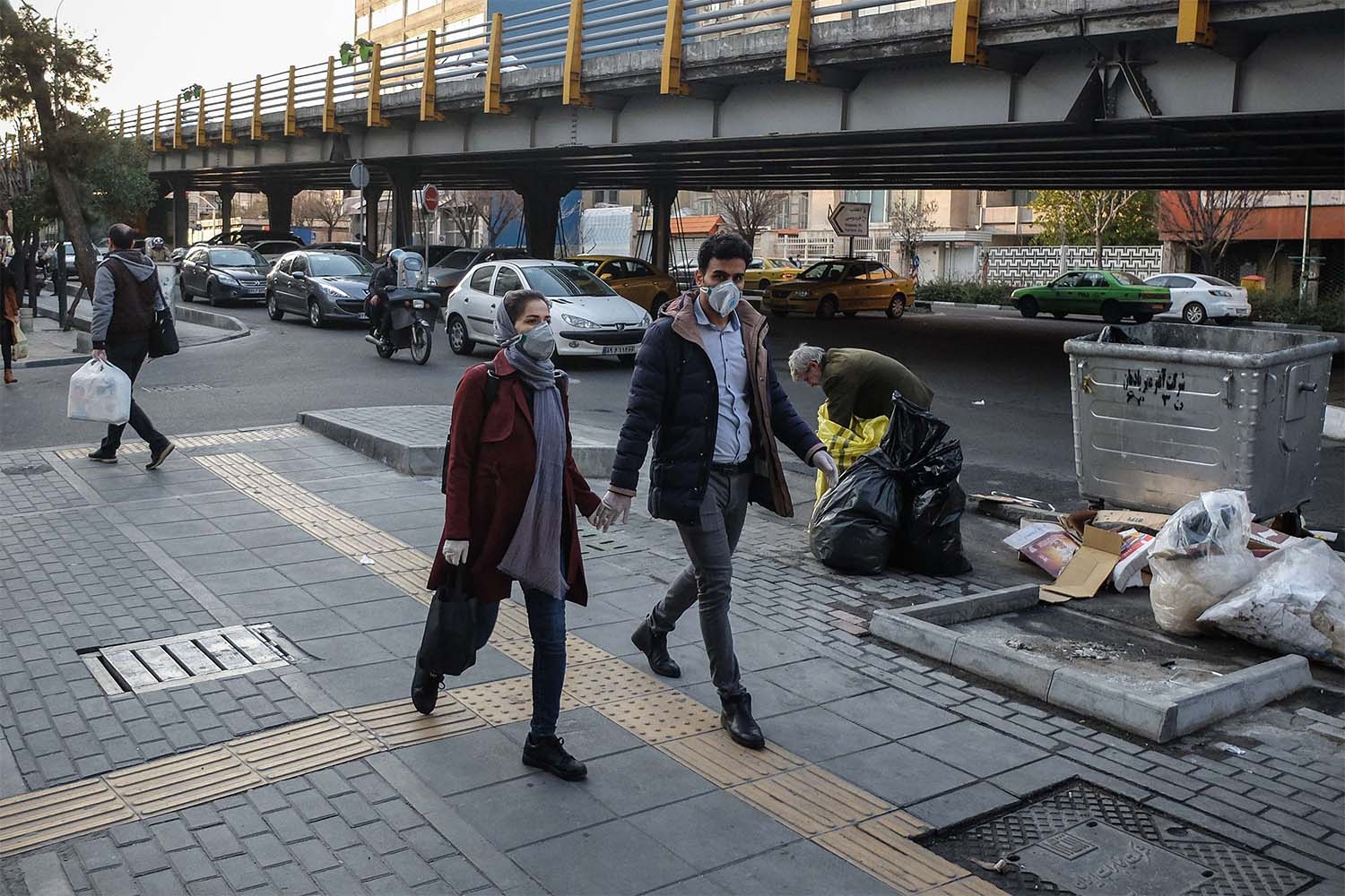 Iranians woman wear face protective masks as they walk on a street in the Tehran business district