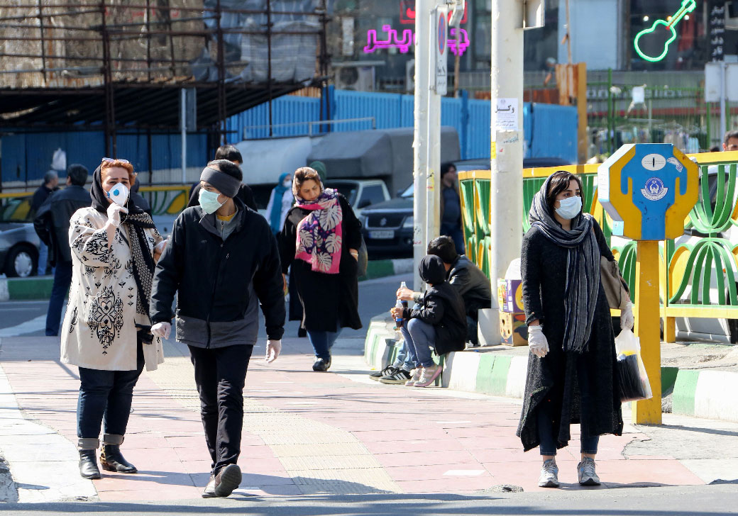 Iranian pedestrians walk while wearing protective masks in Tehran