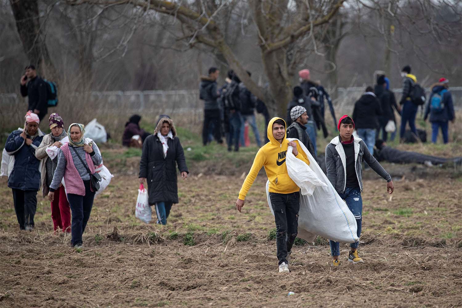 Migrants walk on the field near the Turkey's Pazarkule border crossing with Greece's Kastanies