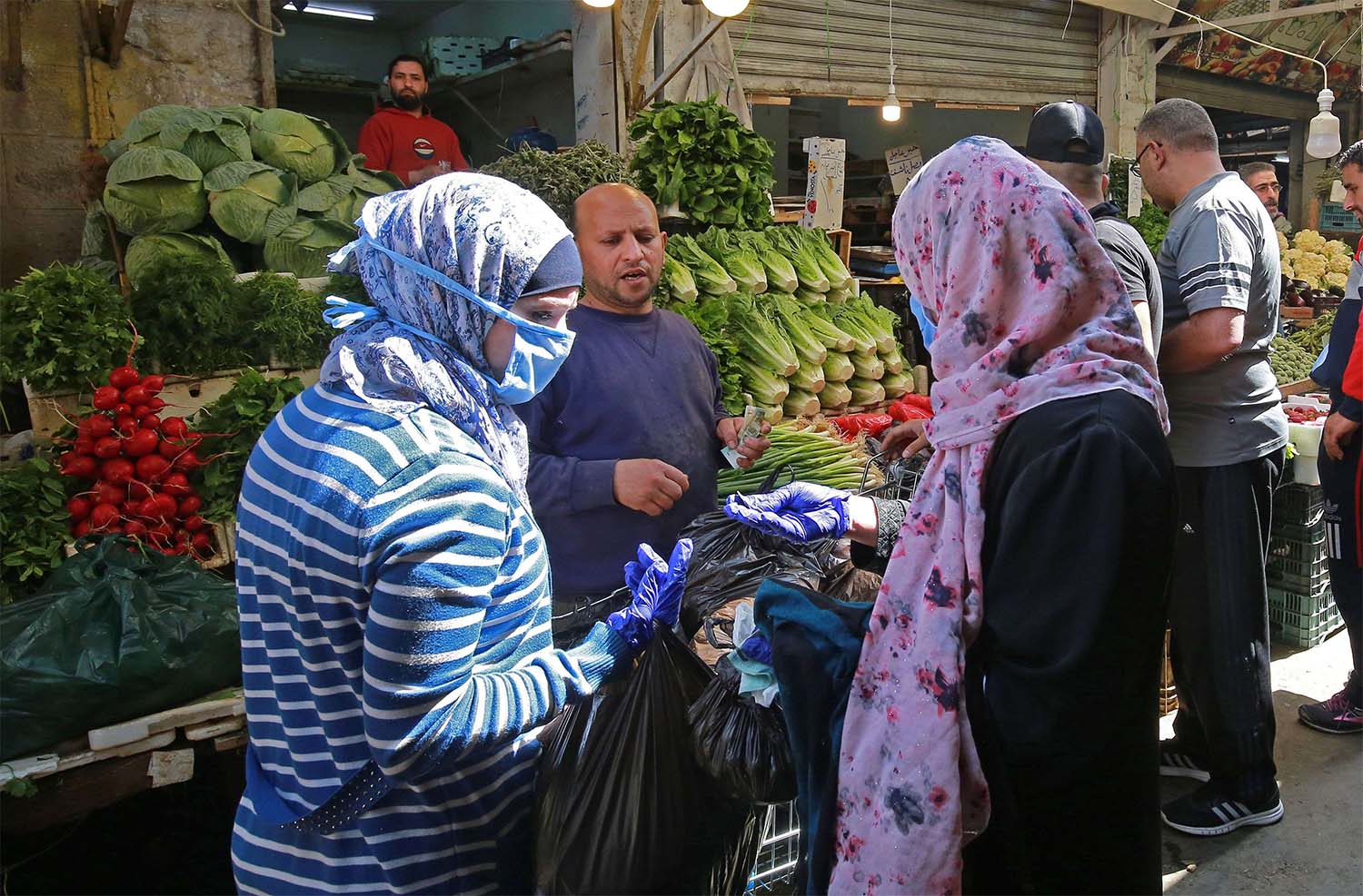 Women buy fresh vegetables at a market in Amman