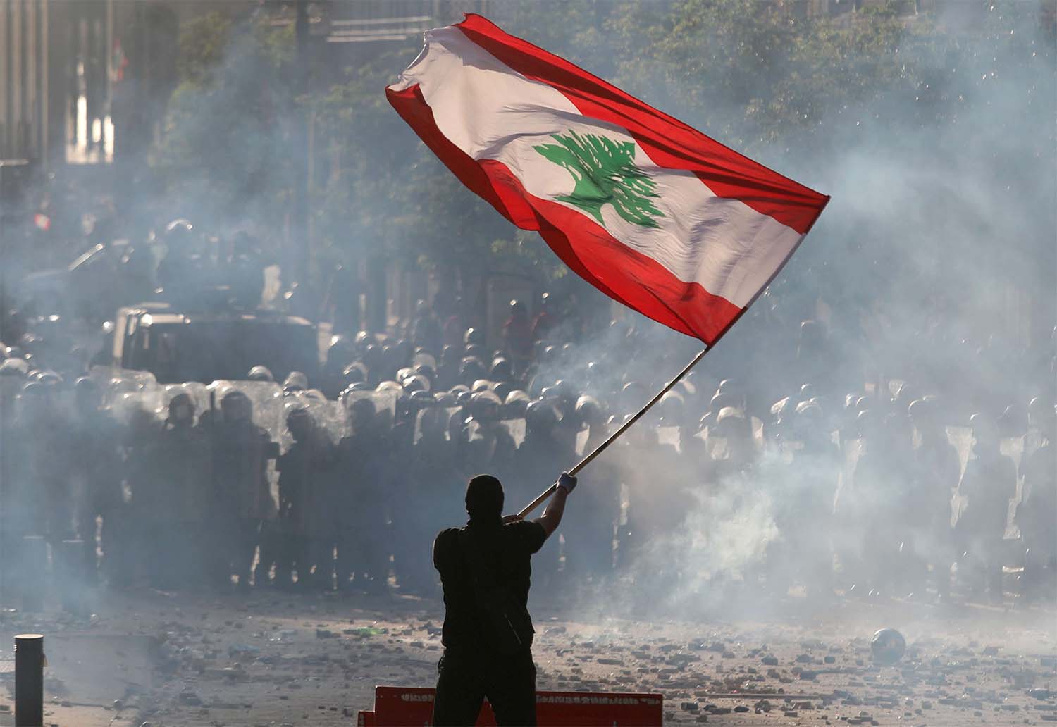 A demonstrator waves the Lebanese flag in front of riot police during a protest in Beirut