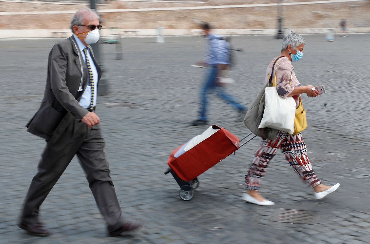 أشخاص يضعون كمامات ويسيرون في شارع بروما في ايطاليا