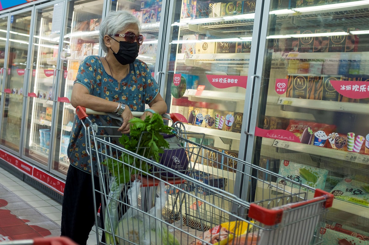 متسوقة صينية أمام ثلاجات الأغذية المجمدة