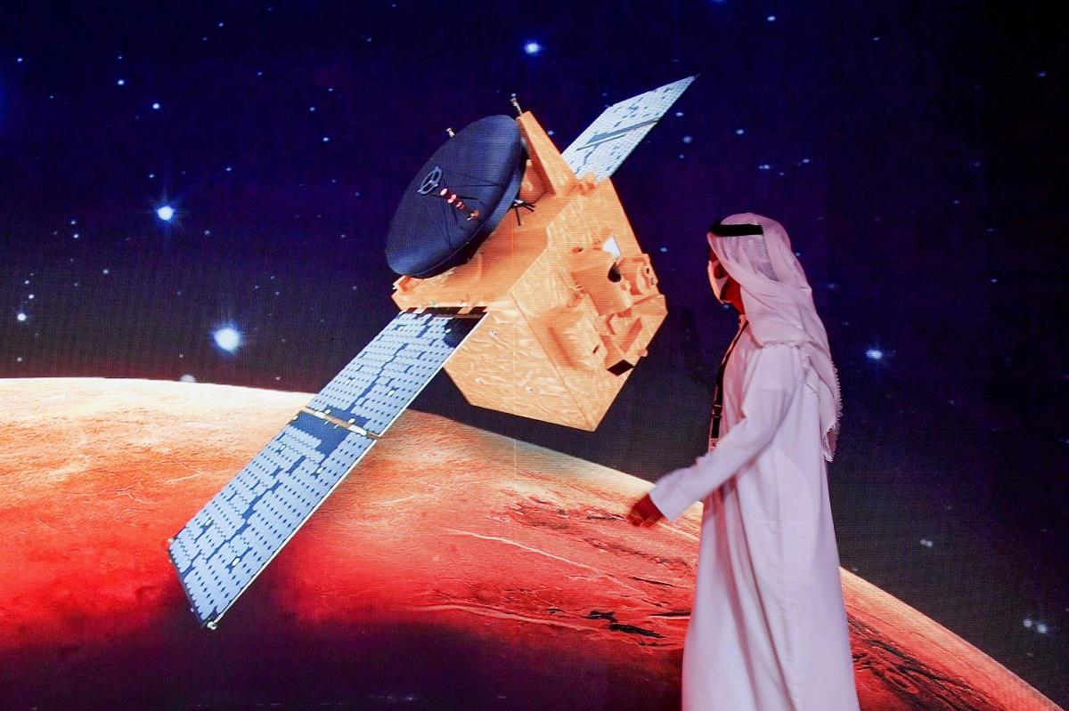 إماراتي يمر عبر شاشة تعرض مسبار الأمل قبيل اطلاقه، في مركز محمد بن راشد للفضاء في دبي