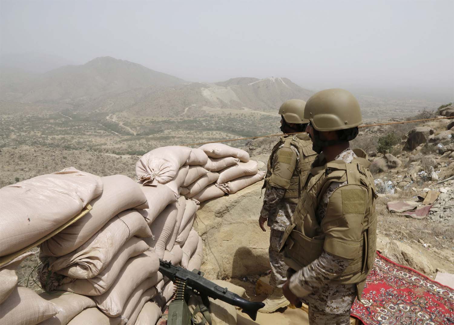 Saudi soldiers stand guard from behind a sandbag barricade at the border with Yemen in Jazan