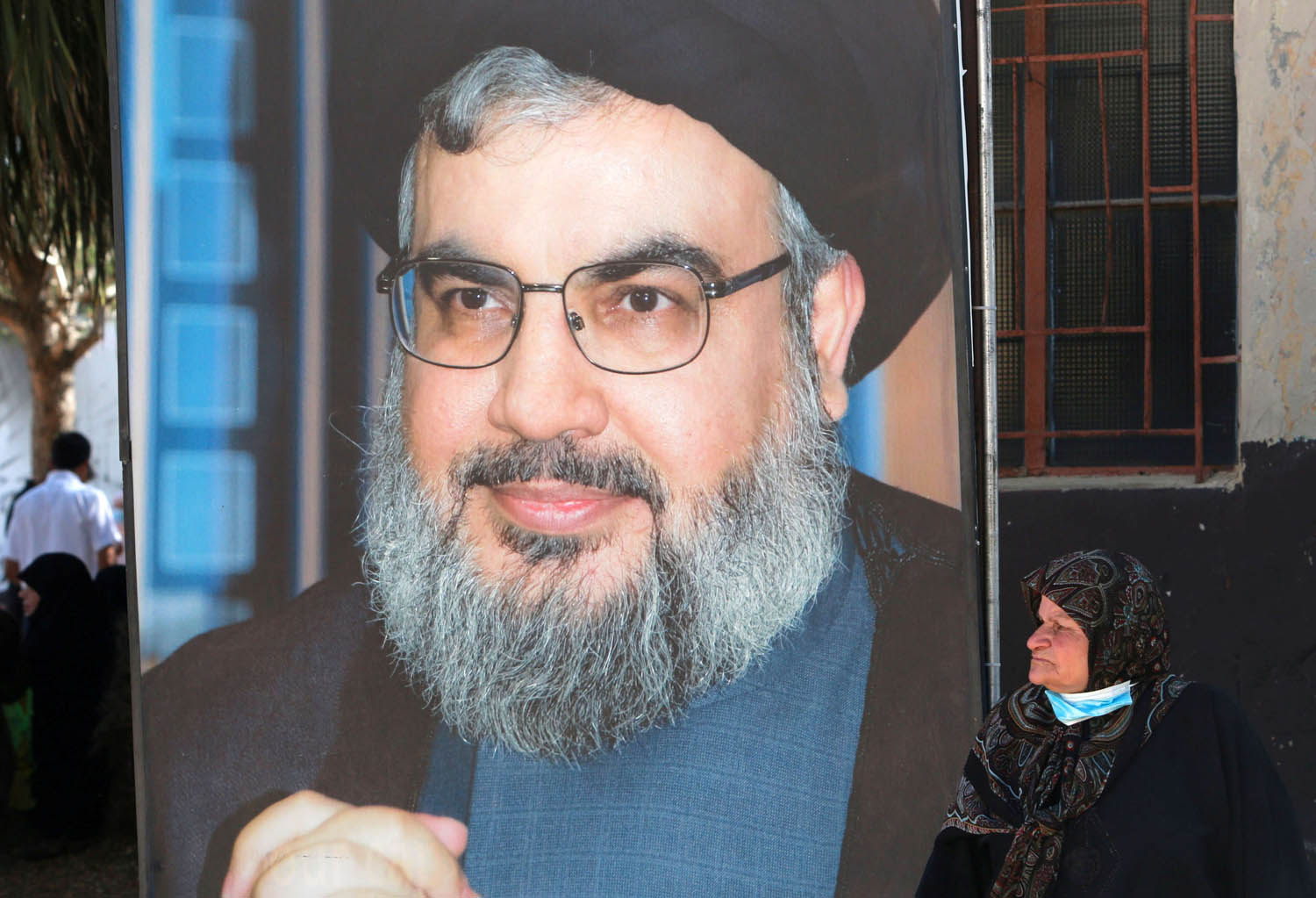 لبنانية تجلس بالقرب من جدارية لحسن نصرالله