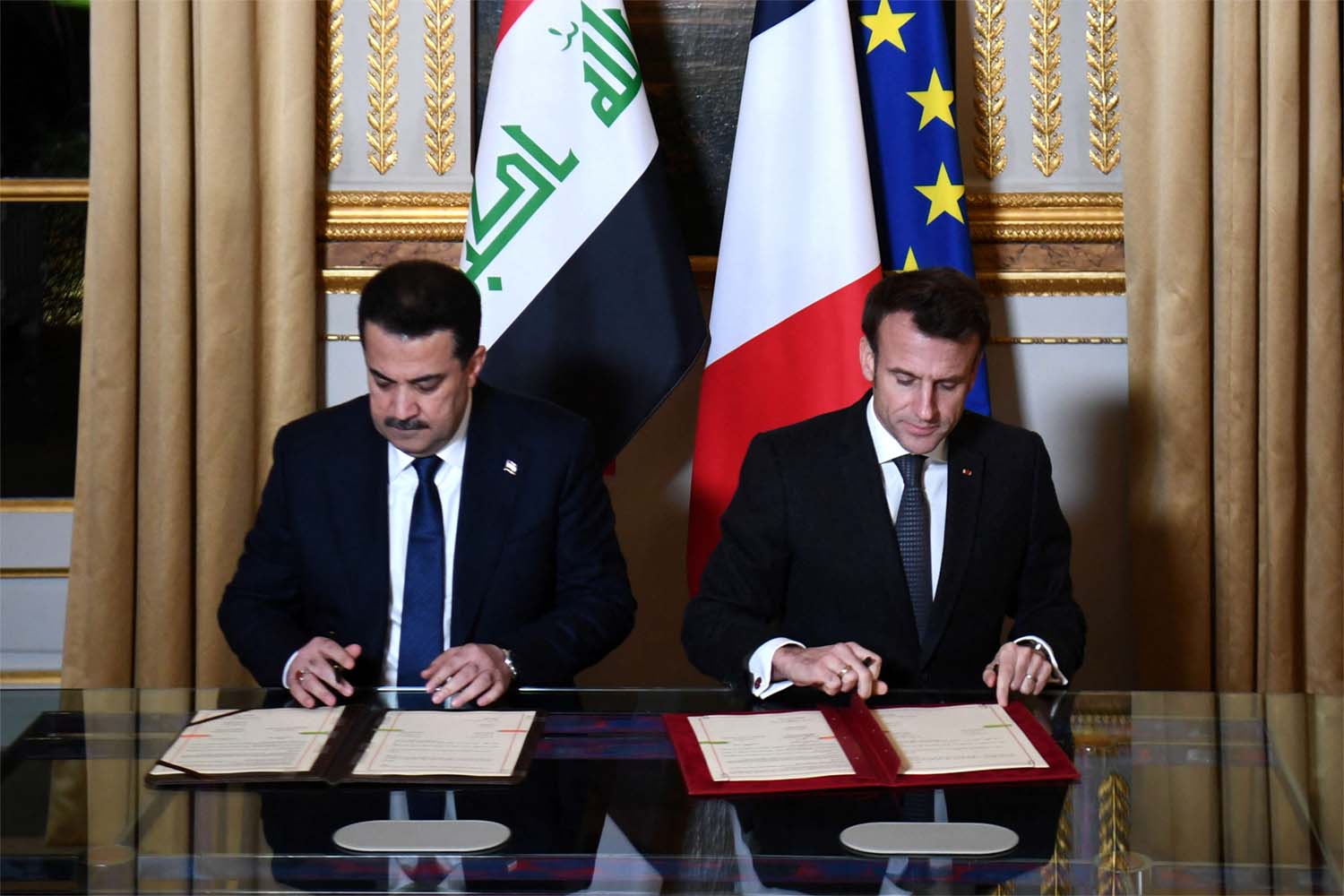 French President Emmanuel Macron and Iraq's Prime Minister Mohammed al-Sudani sign documents at the Elysee Presidential Palace