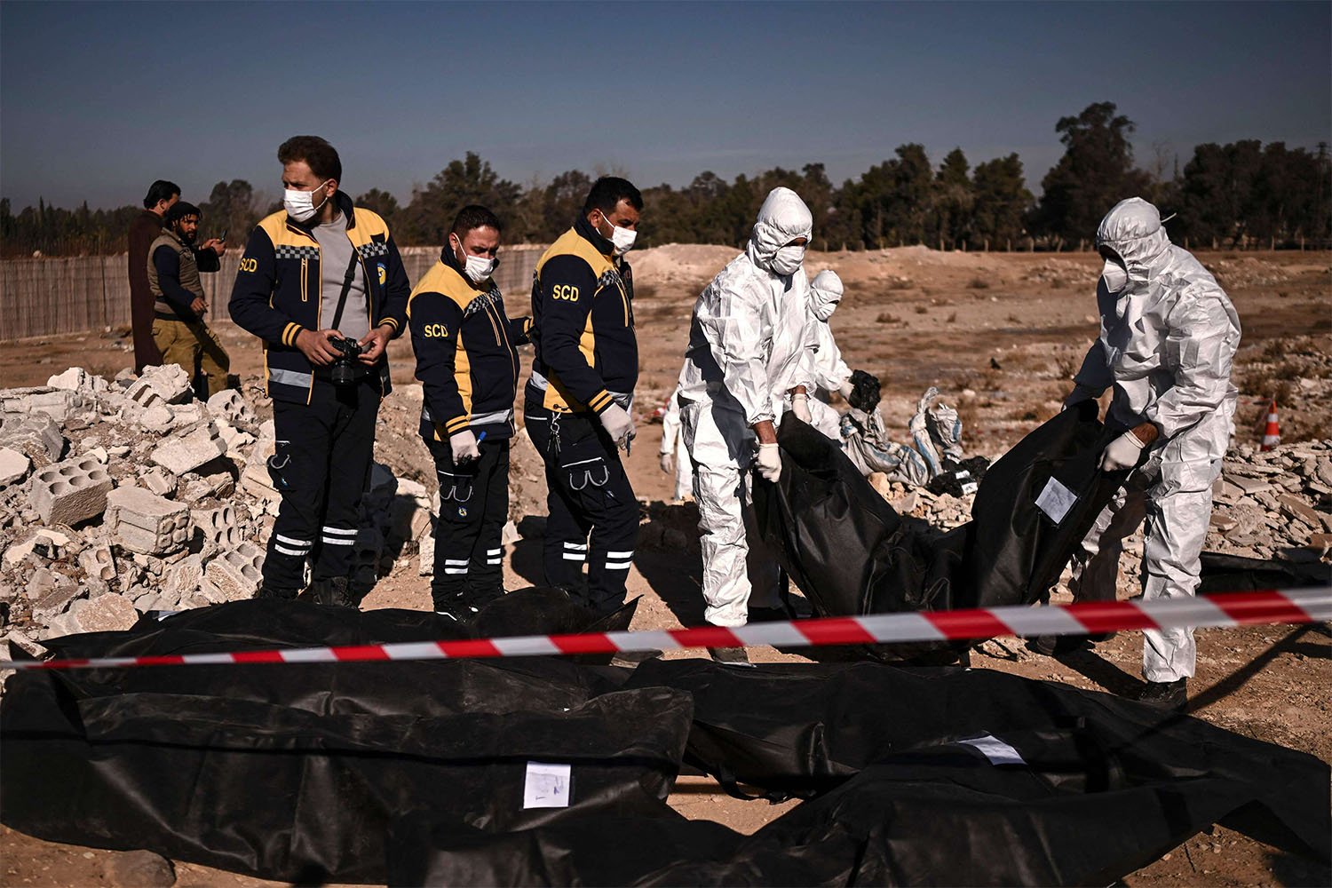 Members of Syria's White Helmets civil defence transport body-bags containing human remains that were recovered from a mass grave in Damascus