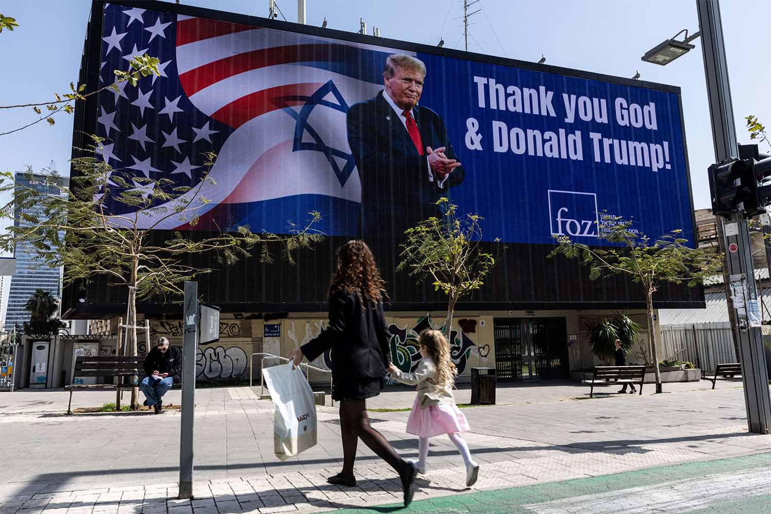 People walk by a billboard commissioned by an evangelical group, which displays a picture of U.S. President Donald Trump with the words Thank you God & Donald Trump, amid the U.S.-Israel conflict with Iran