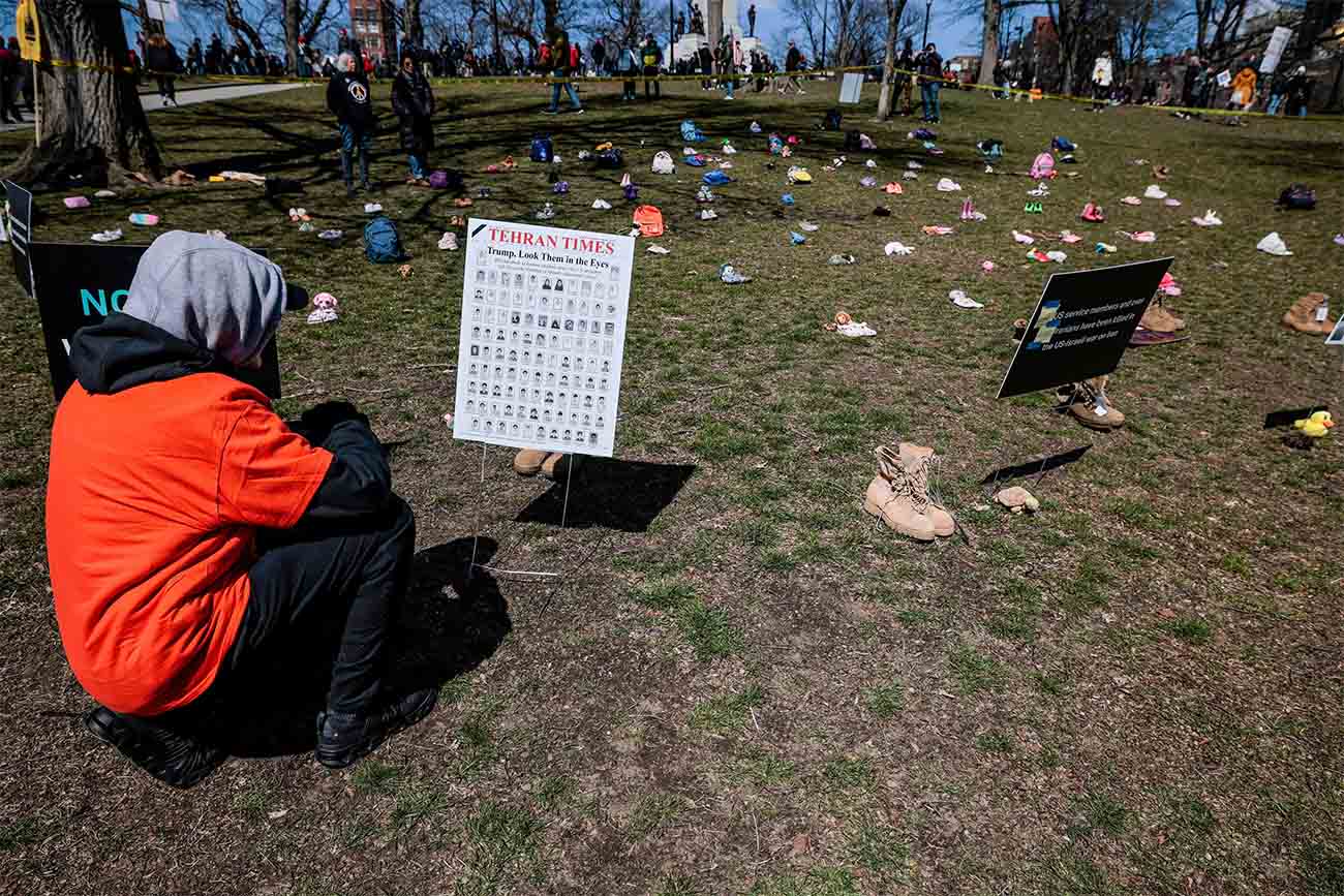 A demonstrator looks at a sign with pictures of students killed in a strike on a girls primary school in Minab in southern Iran, on the day of a No Kings protest against U.S. President Donald Trumps administration policies, in Boston