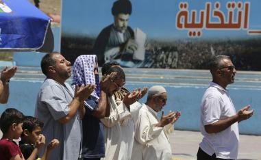 عراقيون يصلون أمام مصلق انتخابي للتيار الصدري