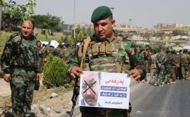 مقاتل من البيشمركه يحمل ملصقا يهاجم فيه رئيس وزراء كردستان السابق برهم صالح