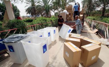 عمال عراقيون يحملون صناديق انتخابية في البصرة