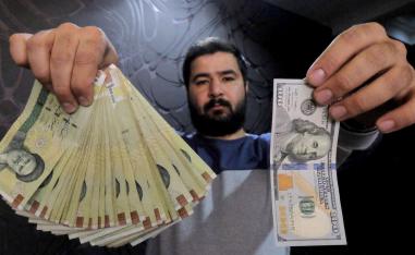 تاجر عملة في طهران يعرض الفرق بين قيمة الدولار وقيمة العملة الوطنية