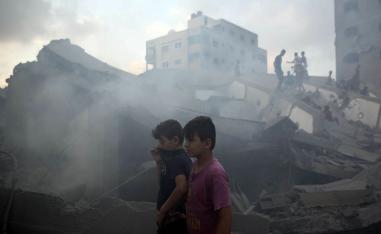 أطفال فلسطينيون بالقرب من مبنى دمرته الغارات الاسرائيلية في غزة