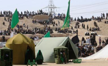 Iraqi people behind tents watch the local actors dressed as ancient warriors re-enact a scene from the 7th century battle of Karbala to commemorate Ashura in Najaf, September 20, 2018.