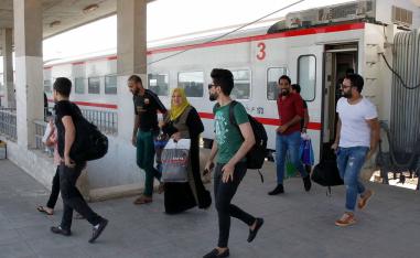 مسافرون ينزلون من القطار بعد وصولهم محطة الفلوجة قادمين من بغداد