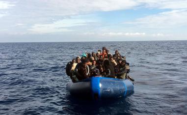Migrants look on from a rubber boat before being rescued in the Mediterranean Sea 