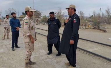 A Pakistani border security official (R) and an Iranian border official meet at Zero Point in the Pakistan-Iran border town of Taftan, on October 16
