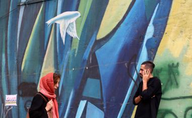 Iranians walk past colourful walls in the capital Tehran.