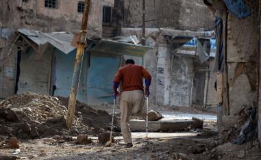 An amputee uses crutches to walk in a debris-strewn street in the old neighbourhood of the northern Iraqi city of Mosul on November 7, 2018.