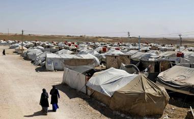 Women walk at a camp for Islamic State (IS) group-affiliated people in the northern Syrian village of Malikiya 